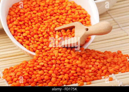 Rosso secco lenticchie in un cucchiaio di legno macro sul tavolo orizzontale Foto Stock