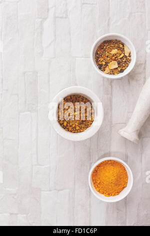 Pezzi di curcuma e curry. Curcuma pezzi in un mortaio con pestello e il curry in ceramica ciotole Foto Stock