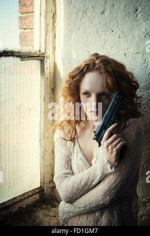 Redhead donna in possesso di una pistola Foto Stock