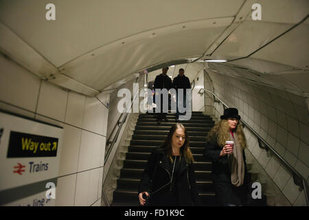 Persone di andare giù per le scale presso la stazione della metropolitana di Londra. Vie di uscita segno sulla parete. Foto Stock