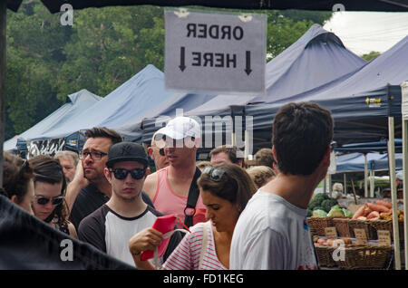 La gente in una coda per fare un ordine per il cibo ad uno stallo del mercato sotto un segno di Oder qui in Australia Foto Stock