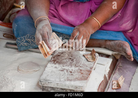 Una foto di un chappati makers le mani e le braccia coperte di farina e contando rupie indiane al di sopra di un legno blocco di trinciatura Foto Stock