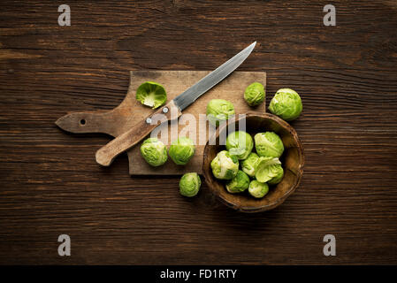 Crudo fresco Il cavoletto di Bruxelles su un sfondo di legno. Foto Stock