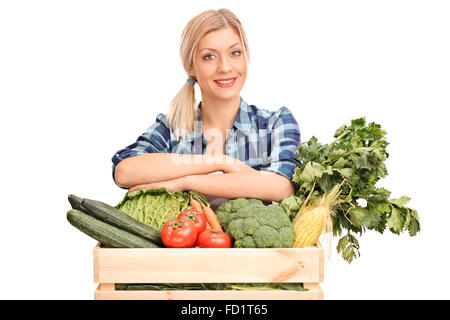 Giovane donna in posa dietro una gabbia in legno pieno di verdure fresche isolati su sfondo bianco Foto Stock