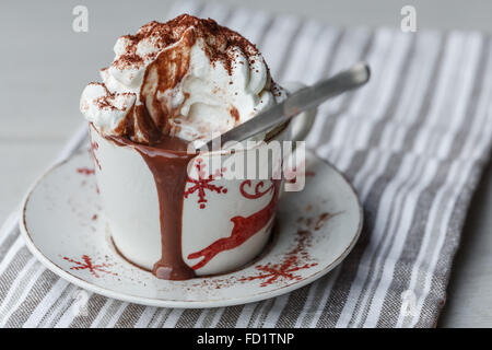 Una tazza di cioccolata calda con panna montata e cacao in polvere Foto Stock