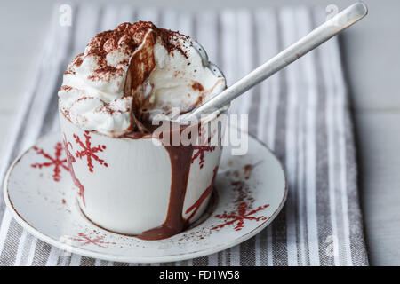 Una tazza di cioccolata calda con panna montata e cacao in polvere Foto Stock