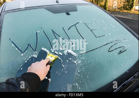Un uomo è la sua pulizia congelati parabrezza auto in inverno Foto Stock