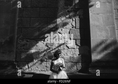 Sposa in posa sul muro di pietra sullo sfondo Foto Stock