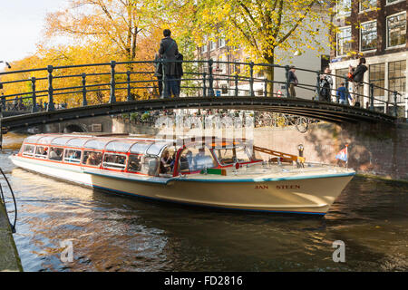 Imbarcazione turistica / barge passando sotto un ponte sul canale di Autunno / caduta con sole / sunny blue sky ad Amsterdam, in Olanda. Paesi Bassi
