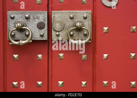 Close-up del dipinto di rosso porta con maniglie in ottone Foto Stock