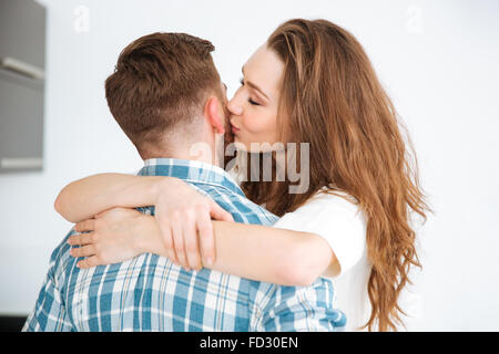 Ritratto di una giovane donna abbracciando e baciando il suo fidanzato a casa Foto Stock