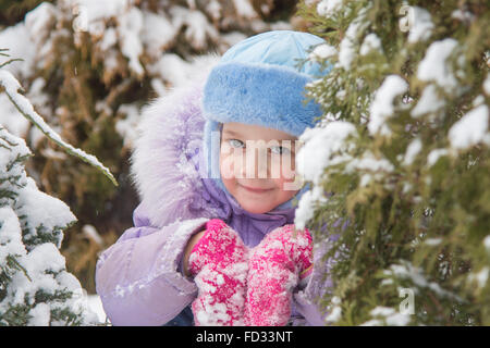 Cinque anni di ragazza in un cumulo di neve neve contro un sfondo innevato alberi Foto Stock