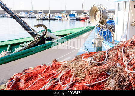 Rosso di pesca sul molo e sulla barca. Rete da pesca e le imbarcazioni in attesa per la piccola marina. Foto Stock