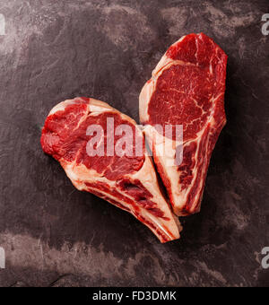 Forma di cuore crudo fresco di carne Ribeye sul tessuto osseo su pietra ardesia sfondo Foto Stock