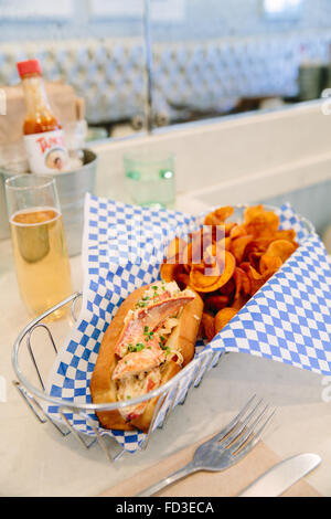 Un rotolo di aragosta e potato chips sono appaiati piacevolmente con lo champagne a piastra blu Oysteria in Santa Monica, California. Foto Stock