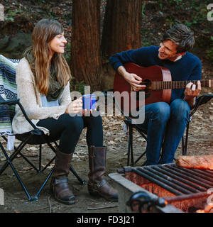 Una giovane coppia si siede vicino al fuoco godersi musica e natura a Big Sur, in California. Foto Stock