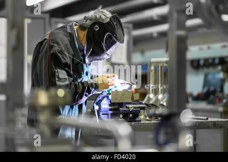 Operaio industriale saldatura in fabbrica di metallo. Foto Stock