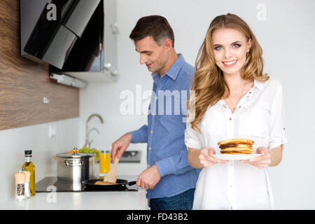 Bella giovane rendendo pancake per colazione sulla cucina insieme Foto Stock