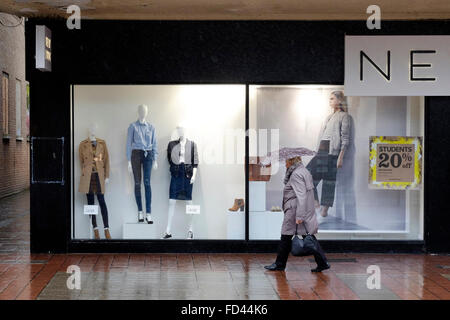 Shopper in pioggia passeggiate passato la finestra di visualizzazione Foto Stock