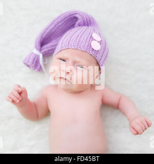 Ritratto di un mese un ragazzo vestito con un cappello viola sullo sfondo bianco Foto Stock