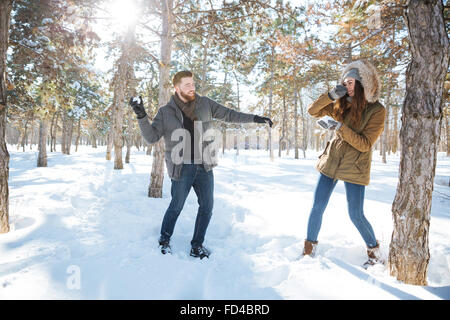 Coppia felice a giocare con la neve in inverno park. Lotta con le palle di neve Foto Stock