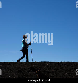 Una donna del Nordic walking sul crinale del vulcano di Samara nel Parco Nazionale del Teide Tenerife, Spagna. Essa utilizza due poli. Foto Stock