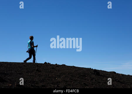 Una donna del Nordic walking sul crinale del vulcano di Samara nel Parco Nazionale del Teide Tenerife, Spagna. Essa utilizza due poli. Foto Stock