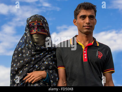 Una donna bandari con suo marito che indossa una maschera tradizionale chiamato il burqa a panjshambe bazar, Hormozgan, Minab, Iran Foto Stock