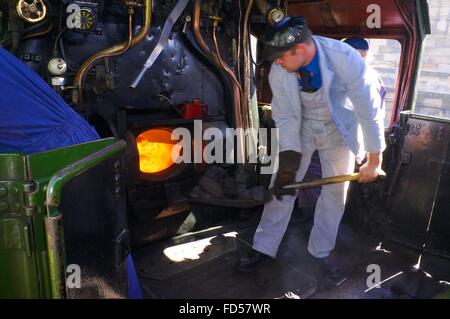 Stoker addensarsi di scatola di fuoco del treno a vapore LMS Principessa incoronazione 46233 Classe Duchessa di Sutherland. Foto Stock