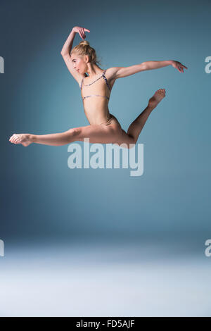 Giovane bella stile moderno ballerina saltando su un sfondo per studio Foto Stock