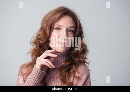 Felice giovane donna che guarda la fotocamera su sfondo grigio Foto Stock