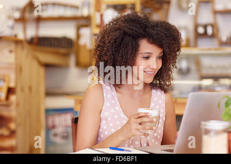 La donna in un coffee shop usando il suo computer portatile Foto Stock