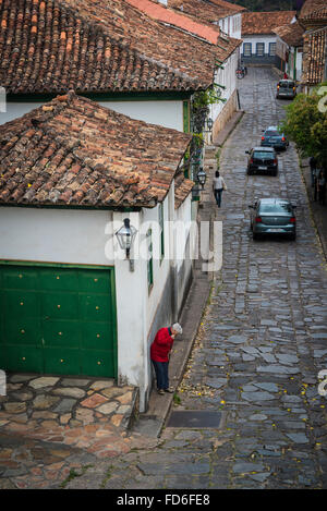 Scena di strada, donna ampie foglie di fronte alla sua casa, Diamantina, Minas Gerais, Brasile Foto Stock