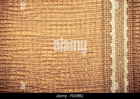 Pizzo sulla cornice naturale materiale mesh, marrone tela ruvida stoffa sfondo. Retrò stile vintage Foto Stock
