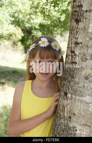 Giovane ragazza vestita in giallo in posa mediante una struttura ad albero. Foto Stock