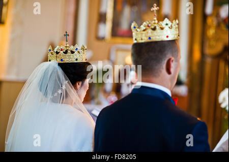 Gli sposi a corone sulla cerimonia di matrimonio in chiesa Foto Stock