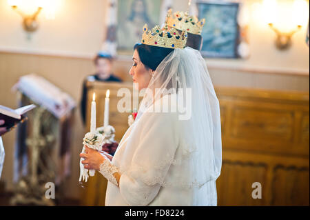 Gli sposi a corone sulla cerimonia di matrimonio in chiesa Foto Stock