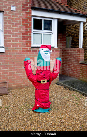 Un cactus vestito in un Babbo Natale vestito al di fuori di una casa. Foto Stock