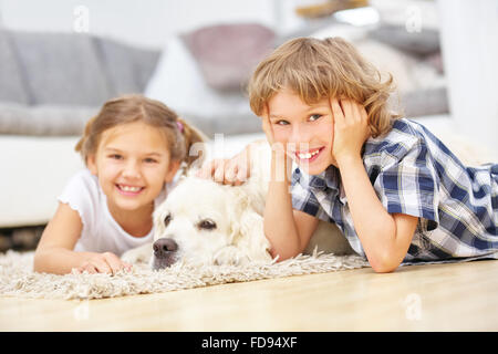 Un ragazzo e una ragazza a giocare con il Golden Retriever cane a casa Foto Stock