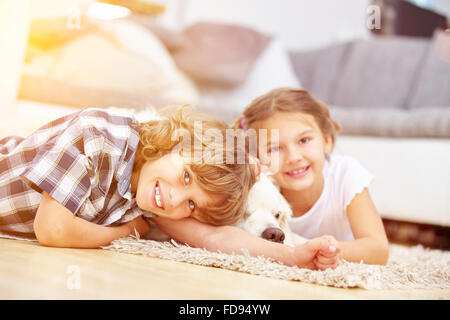 Due felici i bambini giocano in casa con un Golden Retriever cane Foto Stock