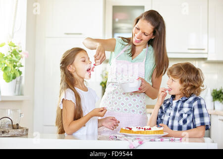 Madre e bambini torta da forno insieme con ribes rosso in cucina Foto Stock
