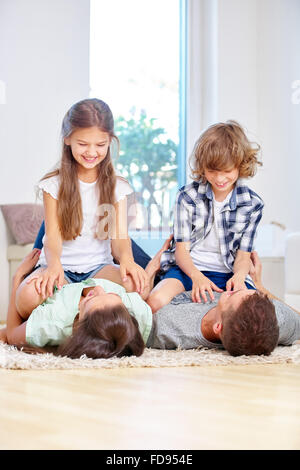 Felice famiglia con due bambini romping intorno a casa nel soggiorno Foto Stock