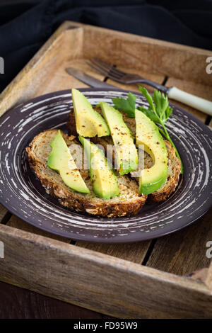 Pane tostato con fette di avocado su piastra. Sana colazione a basso contenuto calorico la dieta alimentare, uno snack o un pranzo Foto Stock