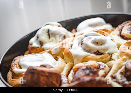 In casa ciambelle alla cannella (cinnabons) con crema di formaggio in salsa di round teglia, close up Foto Stock