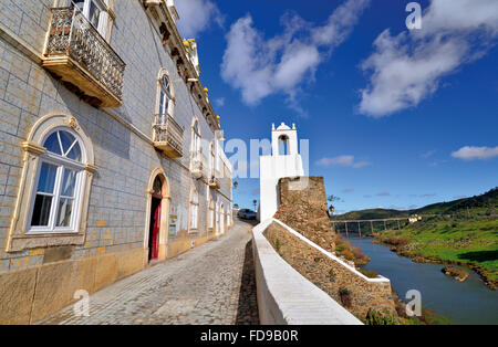 Portogallo Alentejo: Stretta di ciottoli vicolo di pietra al palazzo comunale e Torre do Relógio con vista al fiume Guadiana Foto Stock