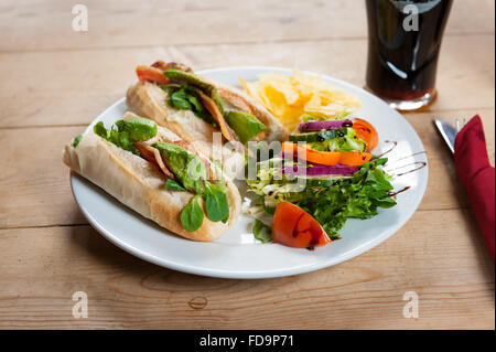 Una pancetta lattuga e pomodoro panino e insalata su una piastra su un tavolo di legno in un pub Inglese. Foto Stock