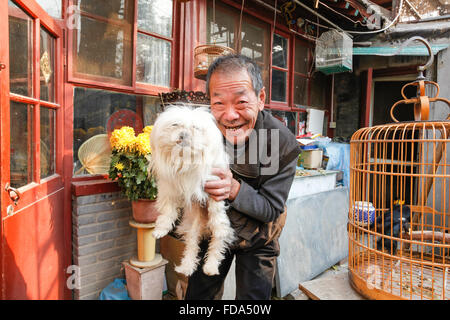 Uomo cinese e il suo cane in un mercato all'aperto nel centro di Pechino, Cina. Foto Stock