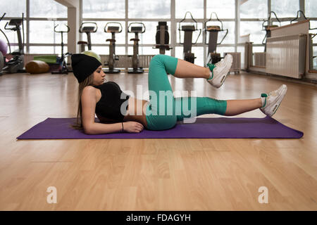 Giovane donna esercitando un suo Abs sulla stuoia in Studio Fitness Foto Stock