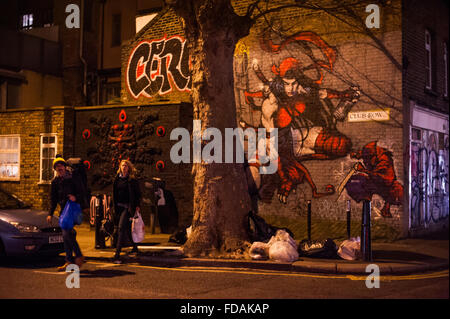 Coppia giovane oltrepassando la street art murale nel trendy Shoreditch, Londra Foto Stock