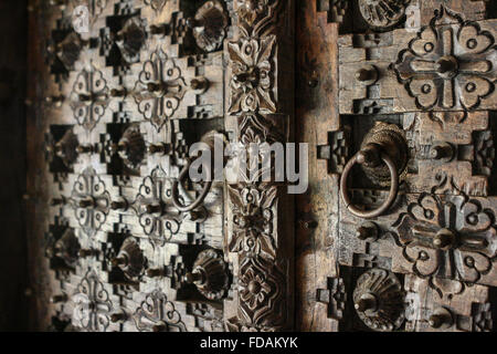 Full frame fino in prossimità di un pesantemente inciso scolpito in legno Porte anteriori con circolare le maniglie della porta tira in India Foto Stock